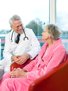 Friendly senior male doctor chatting to a patient.